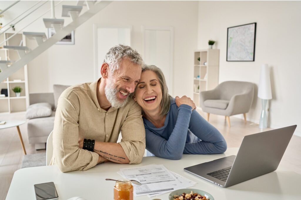 senior couple smiling while looking at laptop